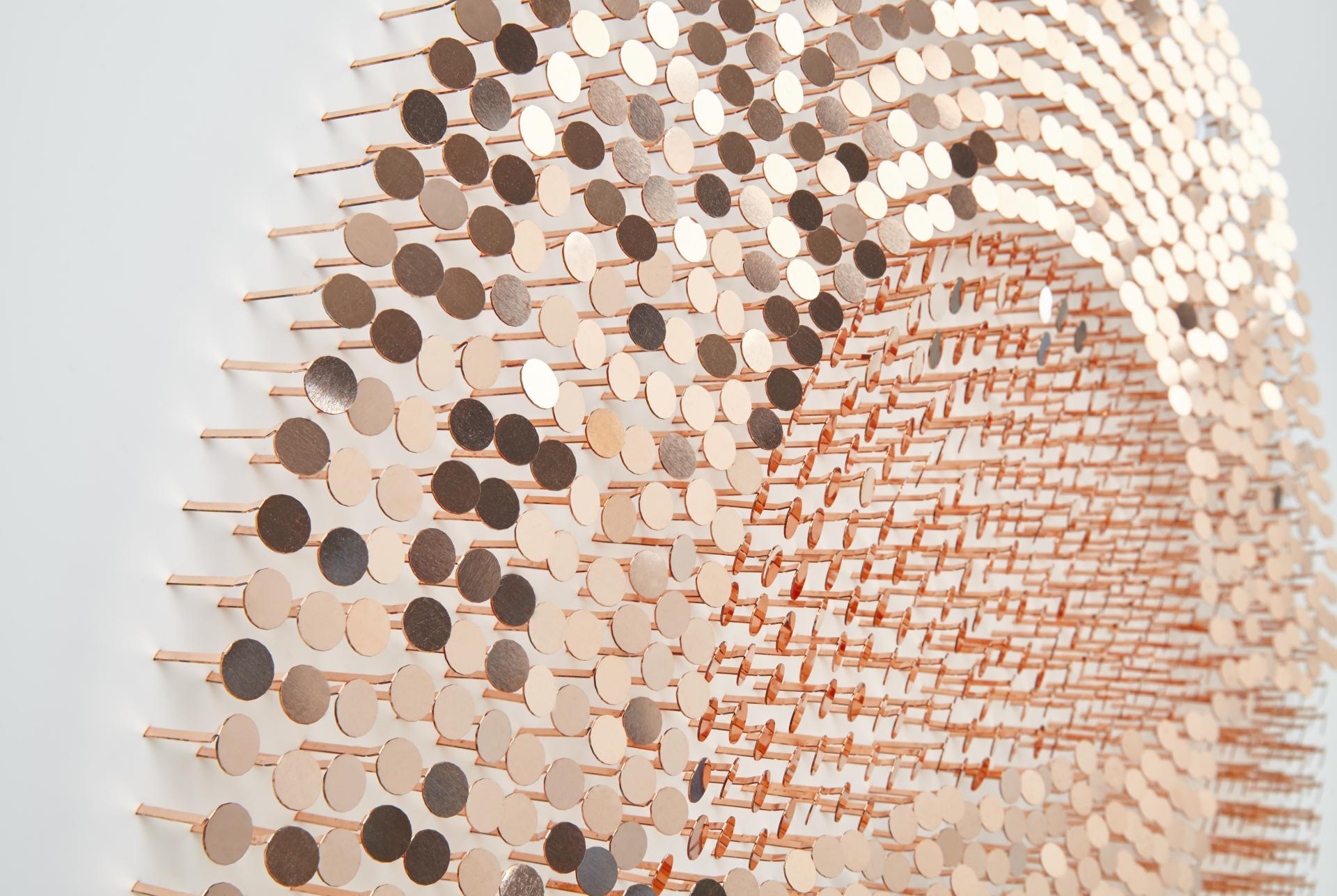Textured wall artwork made of metallic discs, showcasing Giles Miller's innovative approach to surface design and depth.