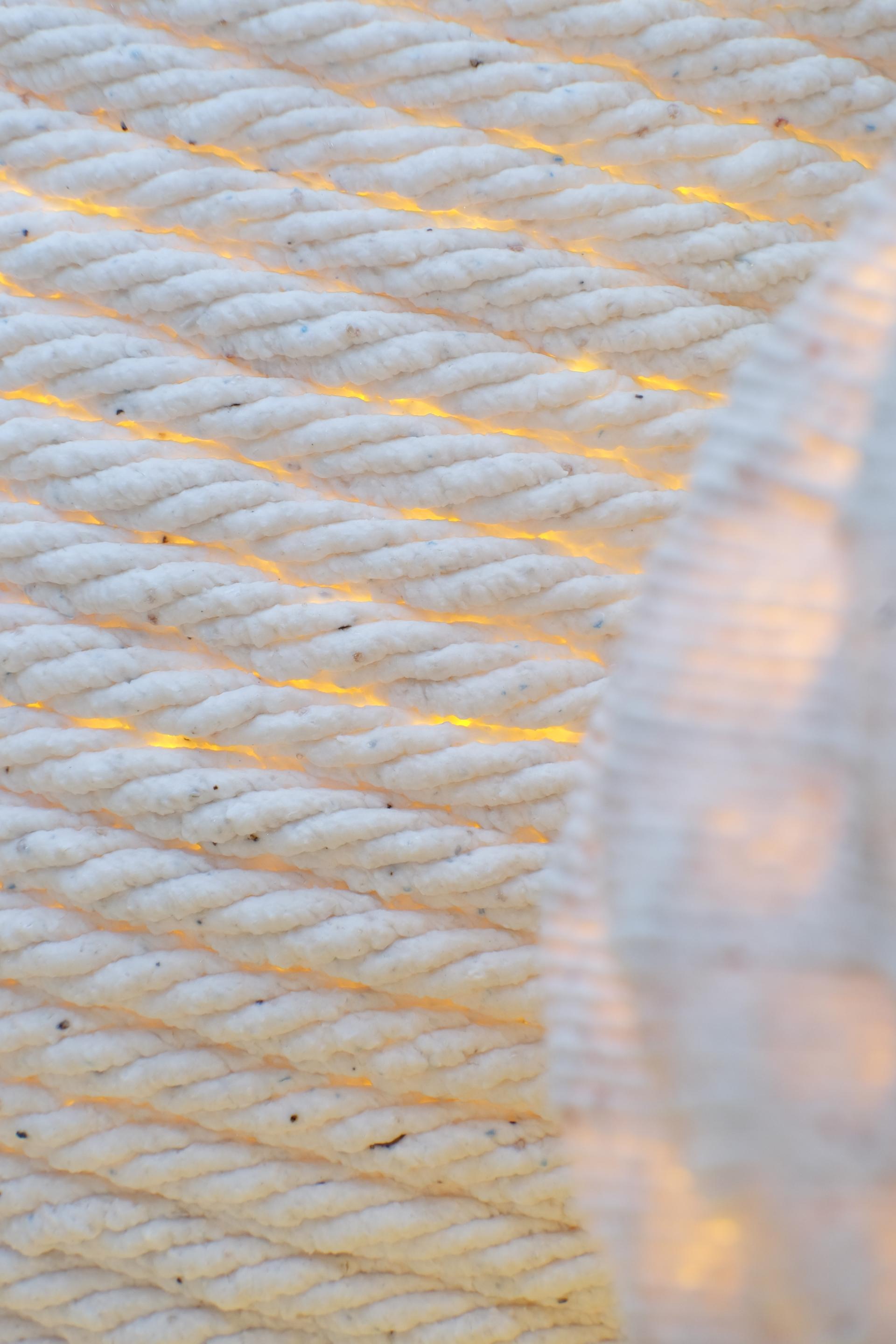 Textured surface of a 3D printed ceramic lamp, displaying sustainable design with soft, warm light shining through.