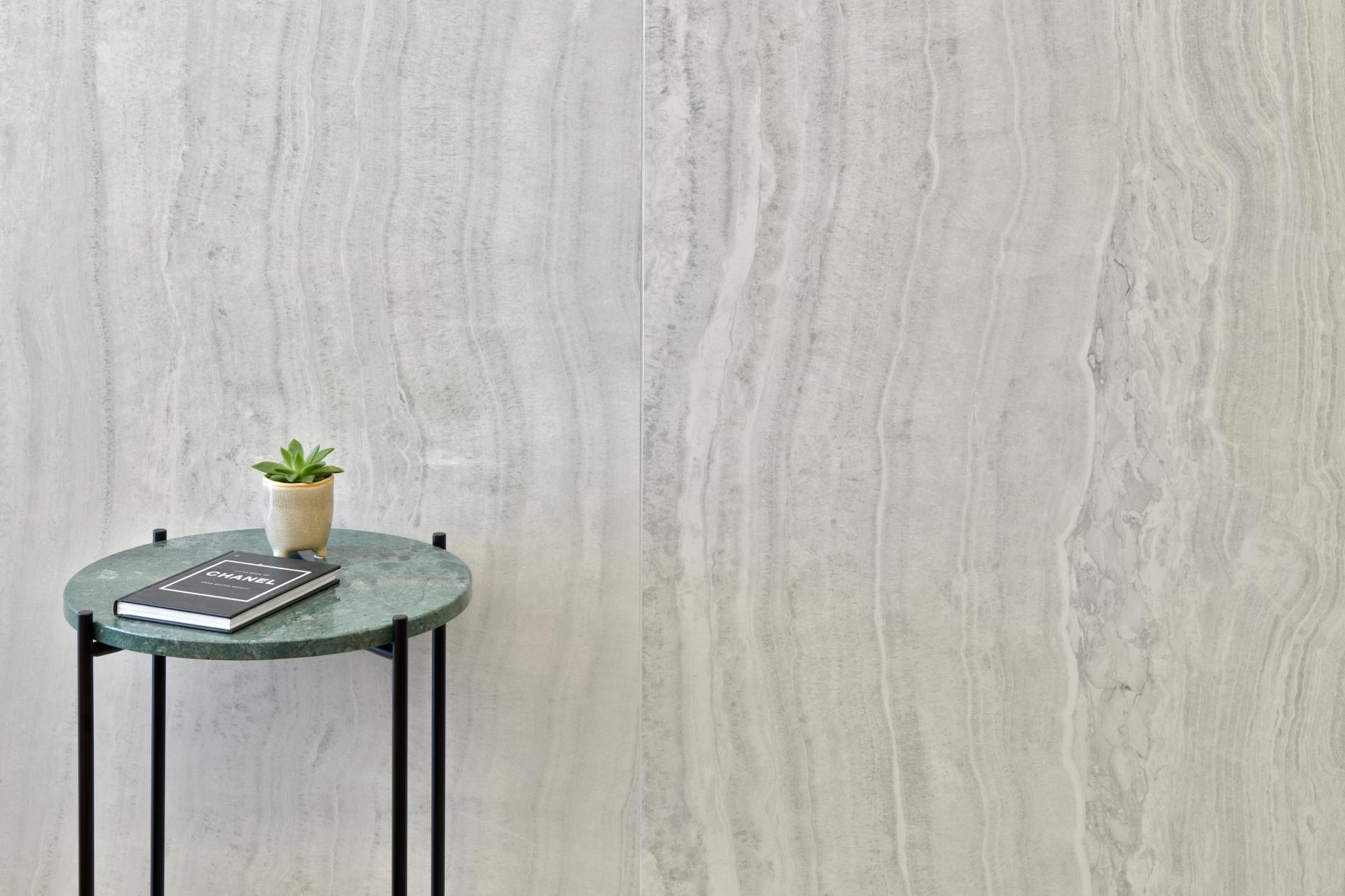 Elegant green marble side table with a small plant and books against a textured gray wall at One Victoria Street.