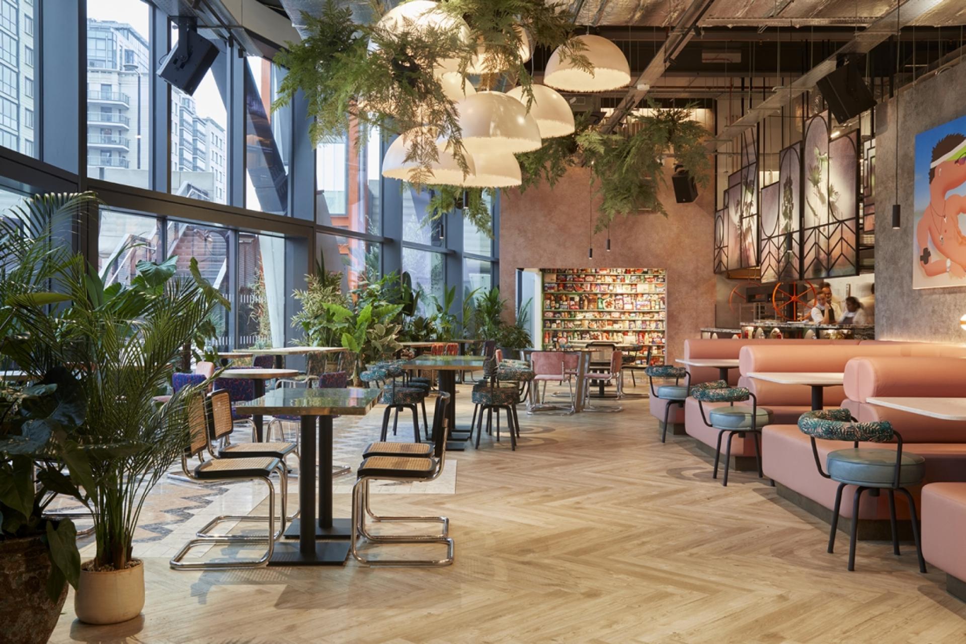 Stylish restaurant interior featuring modern decor, plants, and vibrant seating, highlighting innovative hospitality design trends of 2021.
