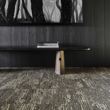 Modern interior featuring a rustic table, textured carpet, and a black and white nature artwork, embodying wabi-sabi aesthetics.
