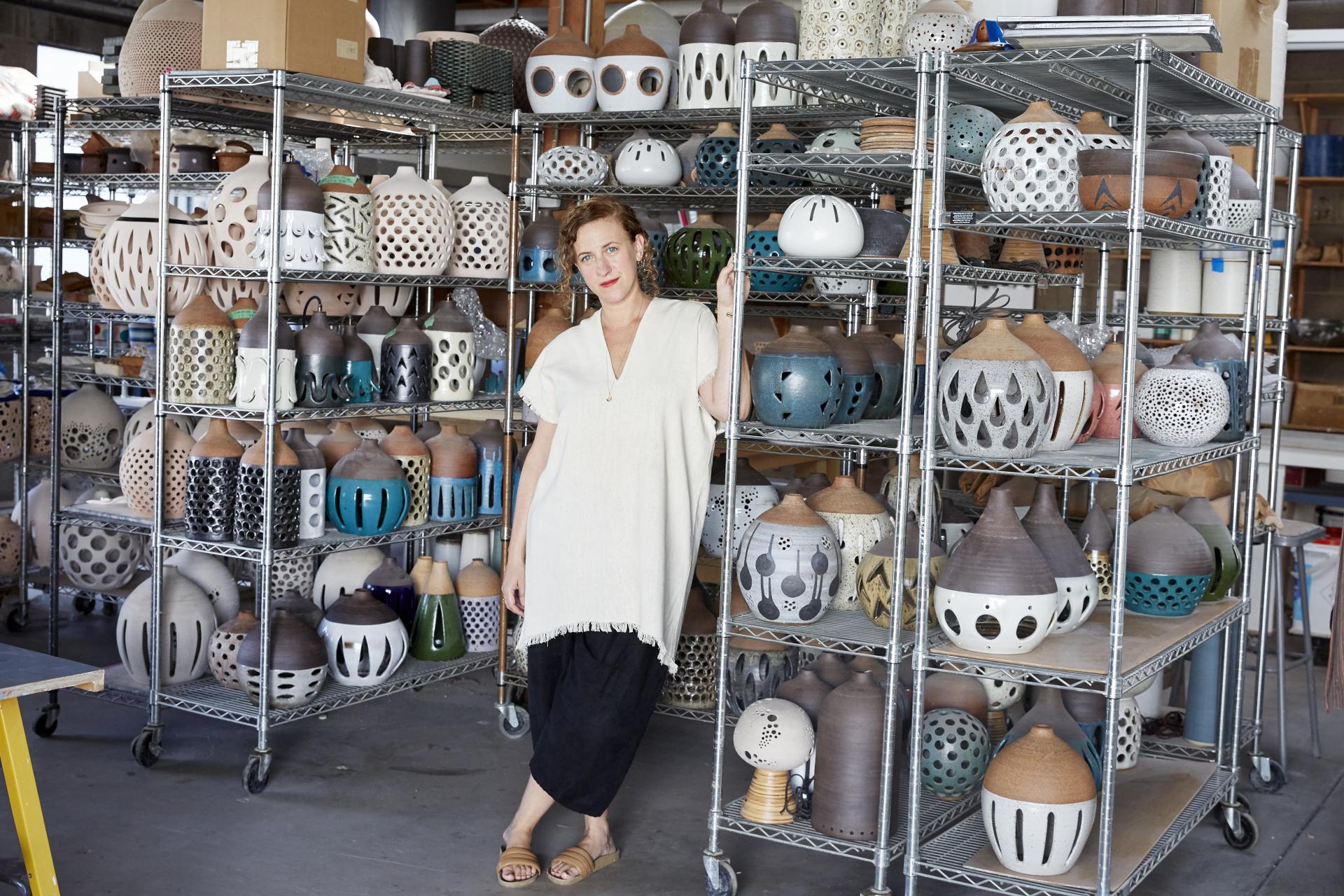 Heather Levine poses in her studio surrounded by intricately designed vintage stoneware ceramics reflecting her artistic style.