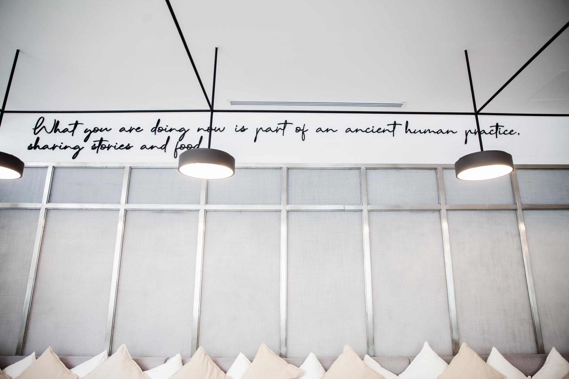 Contemporary interior design of Chunk in Riyadh featuring a wall quote about sharing stories and food.