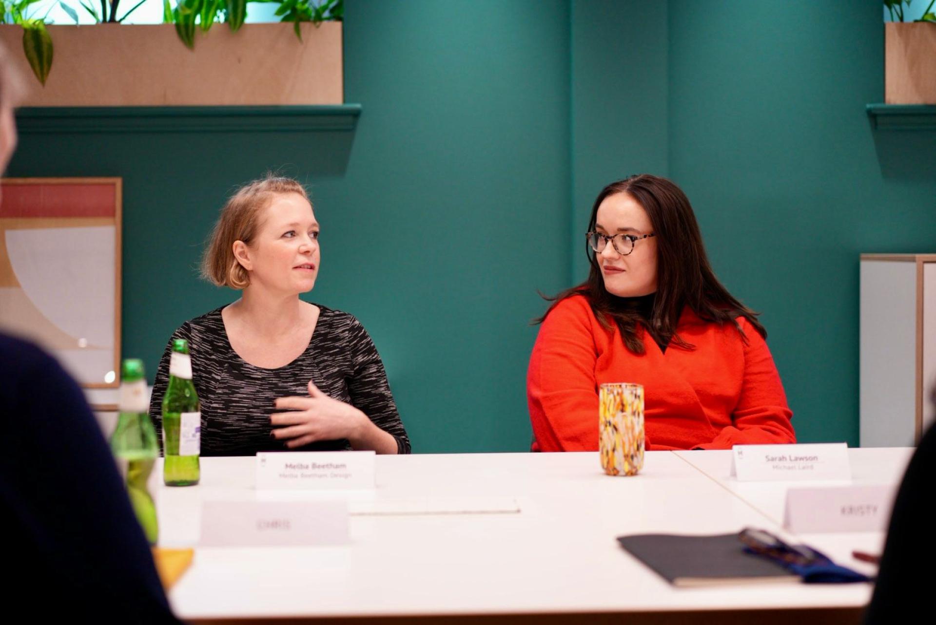 Two women engaged in a discussion during a workplace meeting, emphasizing the importance of flexibility in modern work environments.
