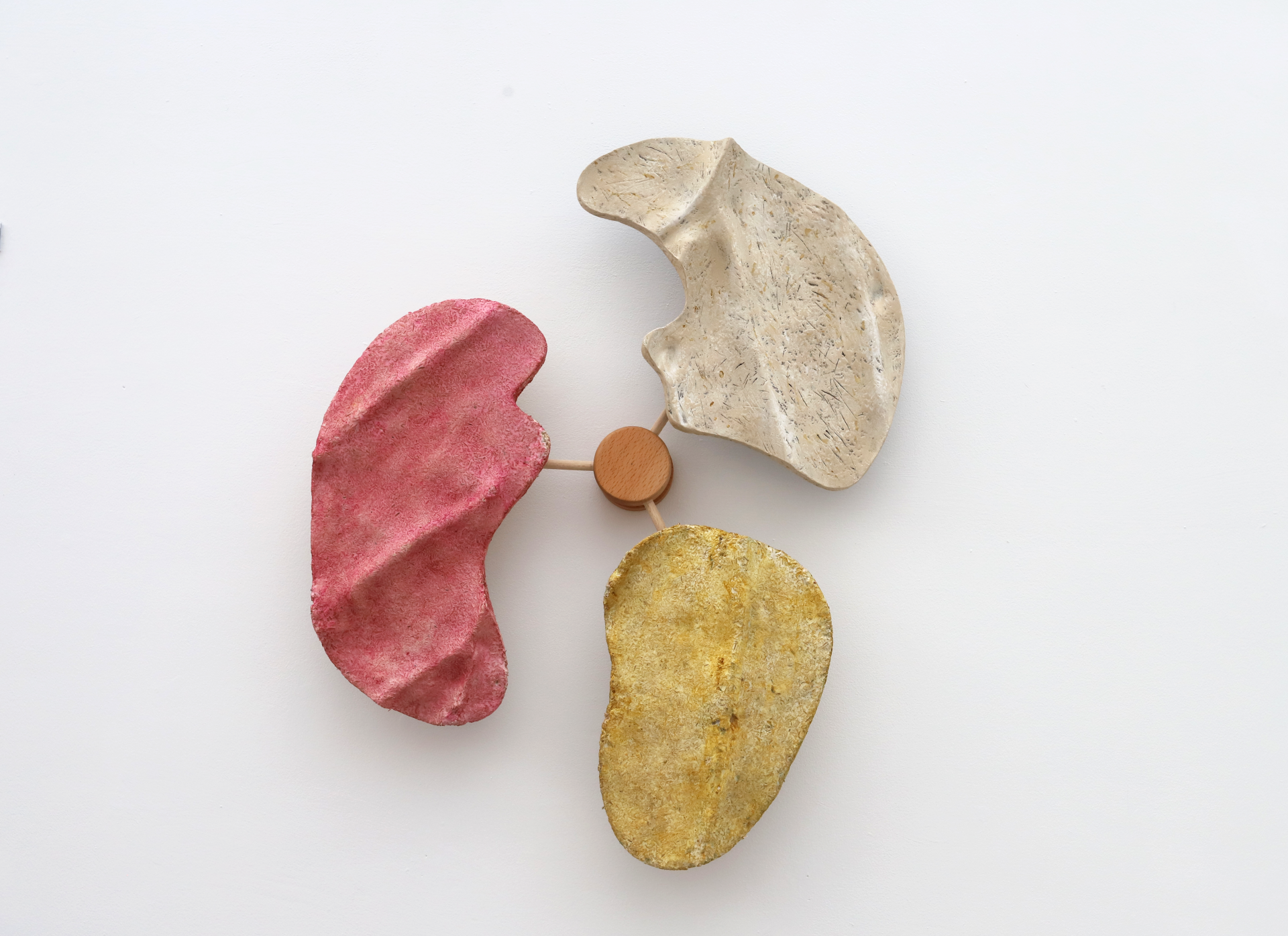 Abstract three-part sculpture in red, yellow, and cream colors, showcasing innovative material design from New Designers 2024.