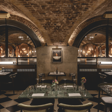 Elegant dining setup at The Libertine, featuring exposed brick arches and stylish decor in London's Royal Exchange.