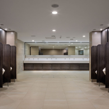 Modern washroom interior at Liverpool Street Station, featuring urinals, sinks, and stylish wood and tile finishes.