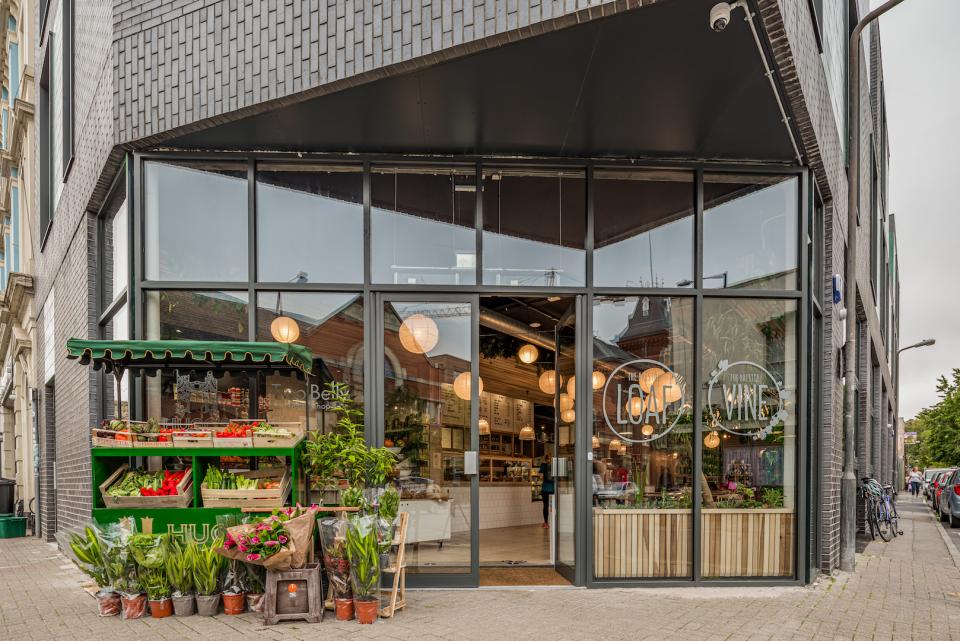 Exterior view of The Bristol Loaf featuring a fresh produce display and inviting atmosphere in a modern setting.