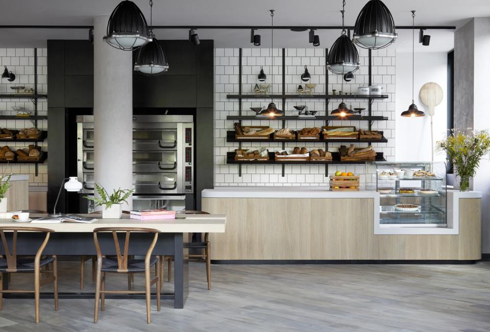 Modern café interior at PURO Kraków Kazimierz featuring stylish wooden furniture, shelves of fresh pastries, and elegant lighting.