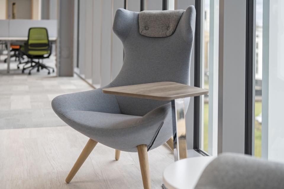 Stylish ergonomic chair with a side table in a modern office, enhancing employee comfort and creativity at AMH Workspace.
