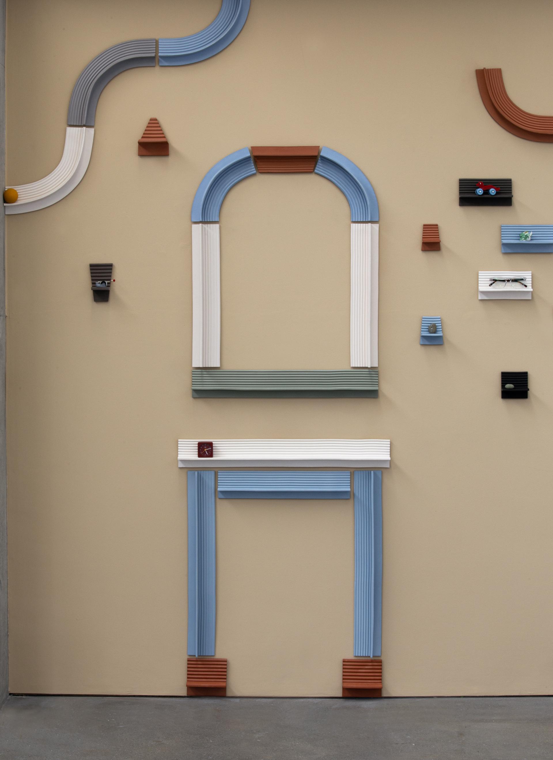 Colorful wall display featuring playful architectural elements, showcasing the creative work of designer Ewan Crallan.