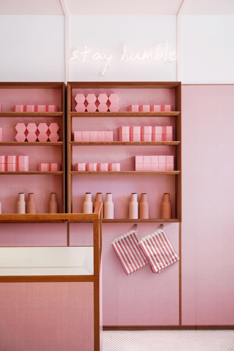 Bright pink shelves display pastel products with a neon 