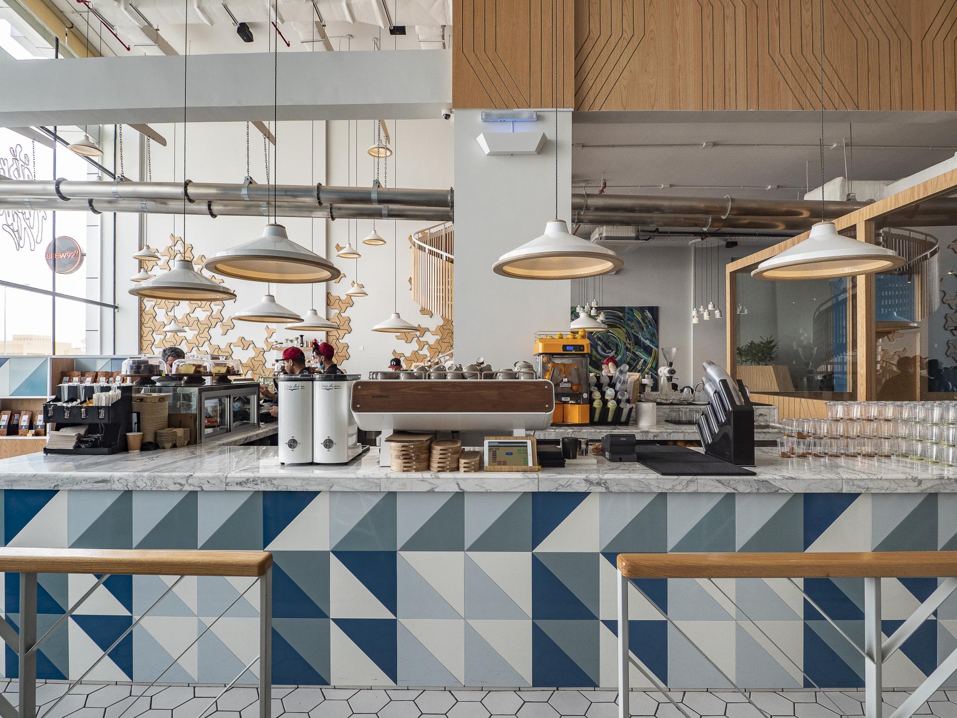 Modern café interior featuring Brew92's distinctive geometric tile design, coffee machines, and bright lighting in Saudi Arabia.