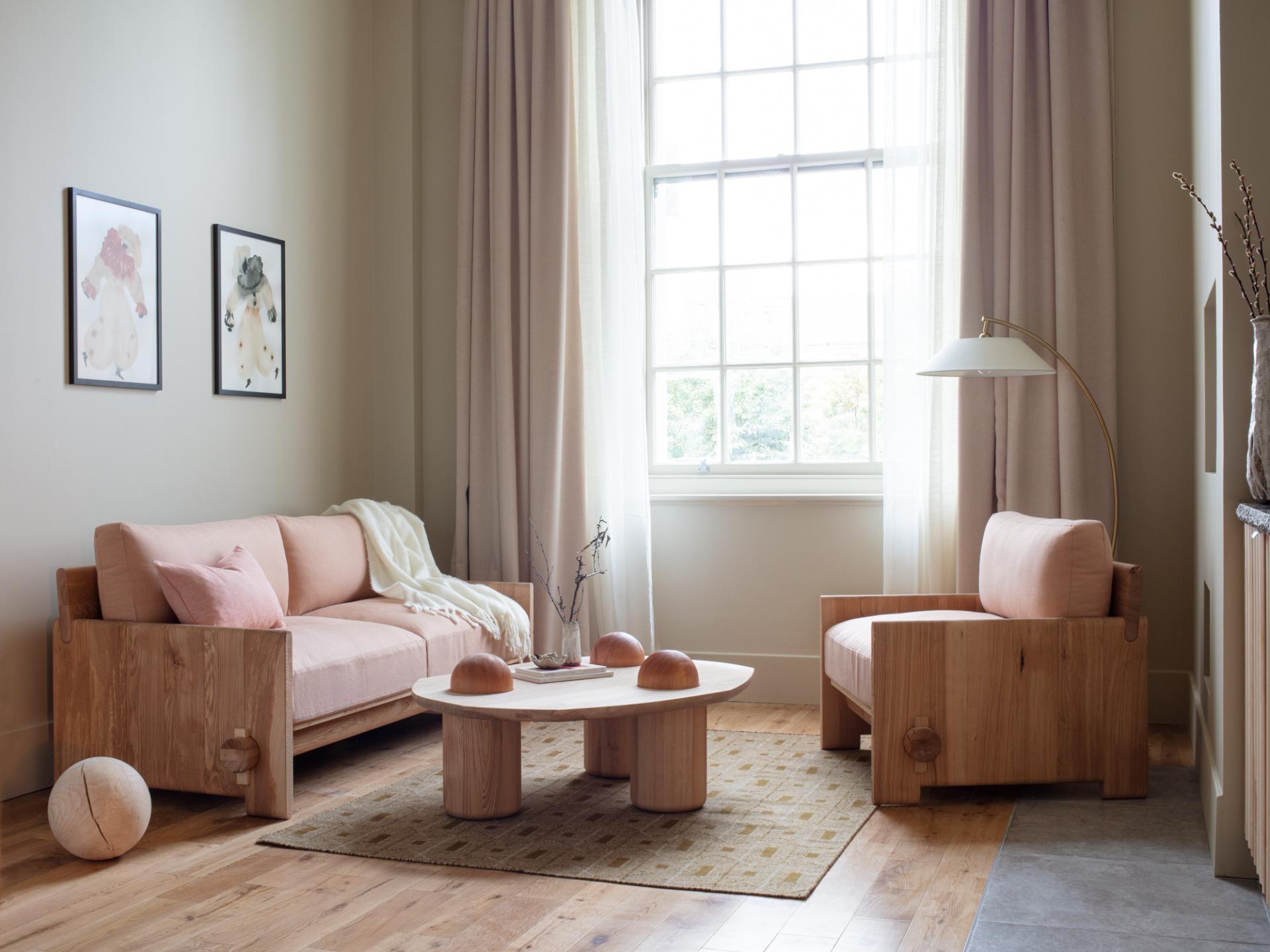 Stylish living room featuring Jan Hendzel's expressive wooden furniture, including a pink sofa and minimalist coffee table.