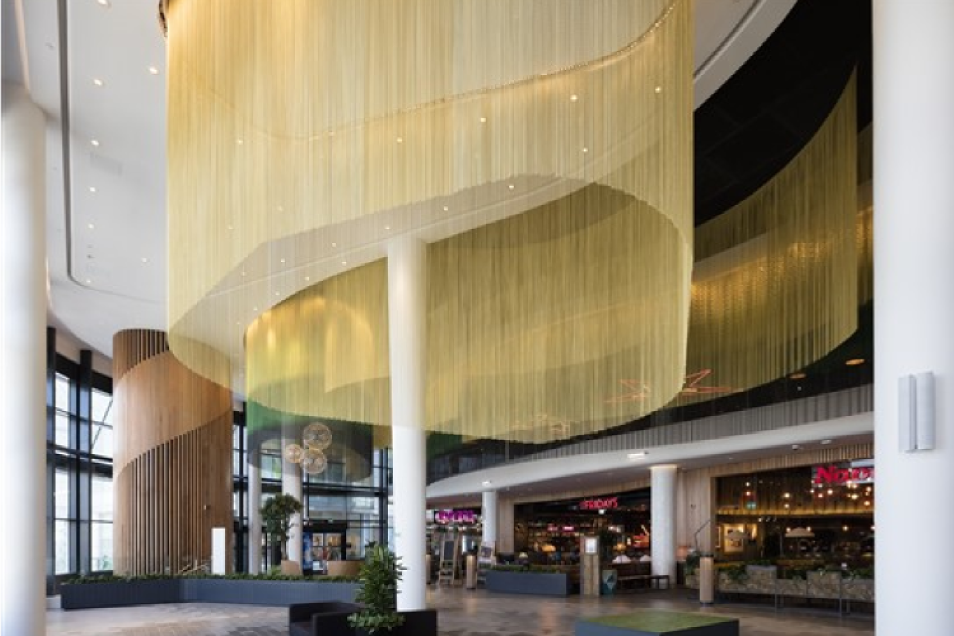 Modern interior design featuring layered ceiling installations with soft lighting and a welcoming entrance at Surface Design Show 2022.