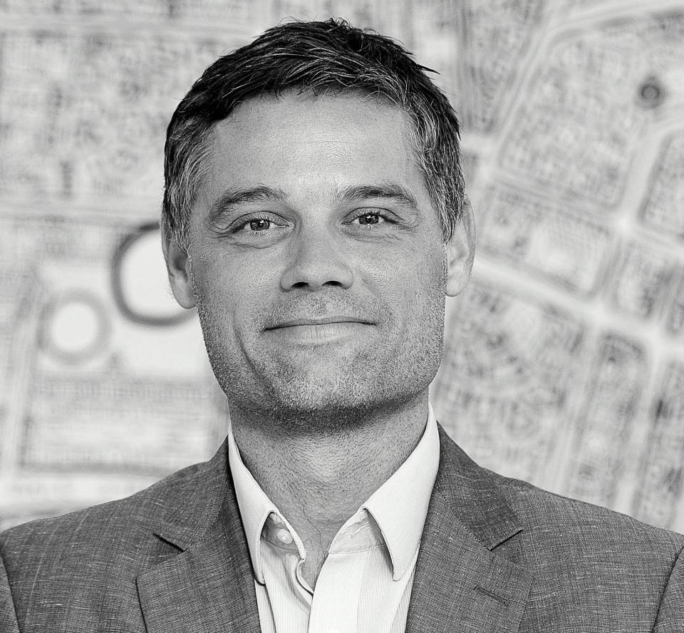 Michael Howard in a professional setting, discussing cooperation over competition in building sustainable urban spaces.