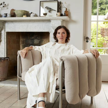 Stylish woman seated in the new Puffy Lounge Chair by Hem, showcasing modern design in a bright interior.