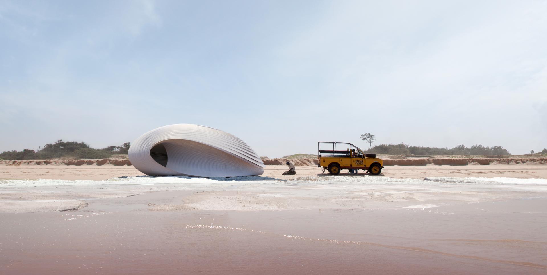 Innovative 3D-printed structure on a beach, with a yellow vehicle nearby, showcasing advancements in construction technology.