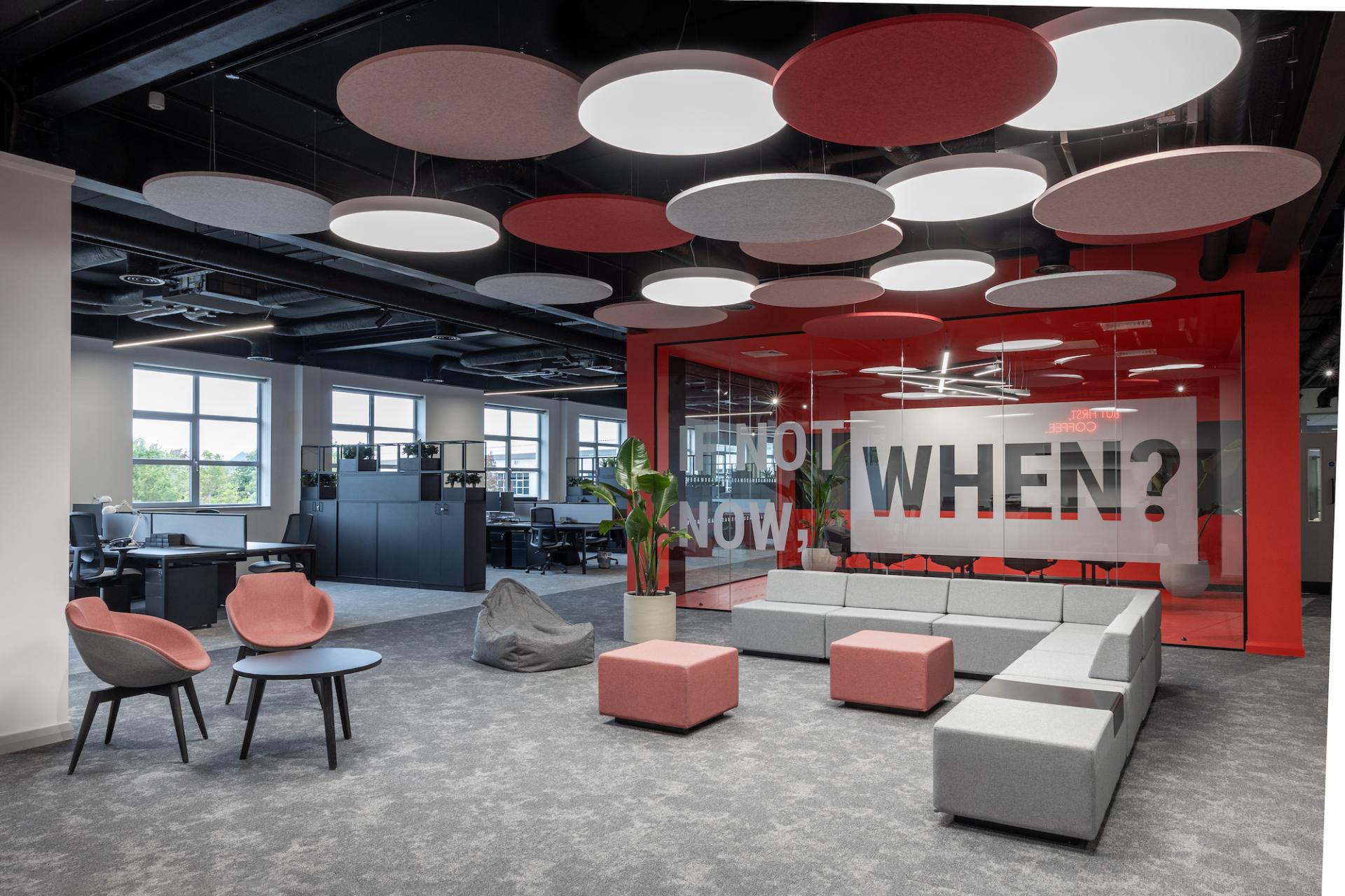 Modern office interior showcasing collaborative workspace design with colorful seating and innovative acoustic features.