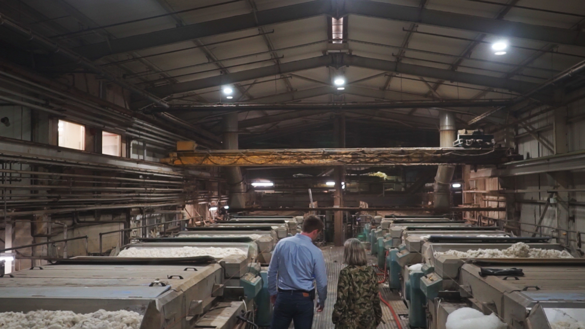 Visitors observe the wool processing area, highlighting the journey of British wool from sheep to finished products.