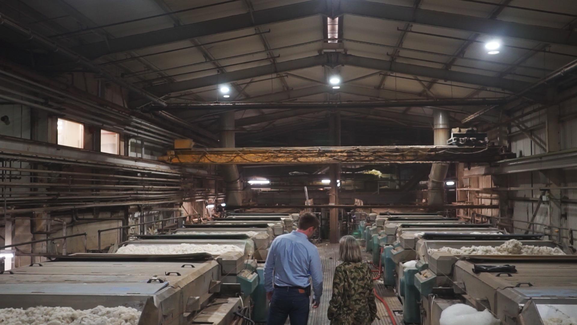 Visitors observe the wool processing area, highlighting the journey of British wool from sheep to finished products.
