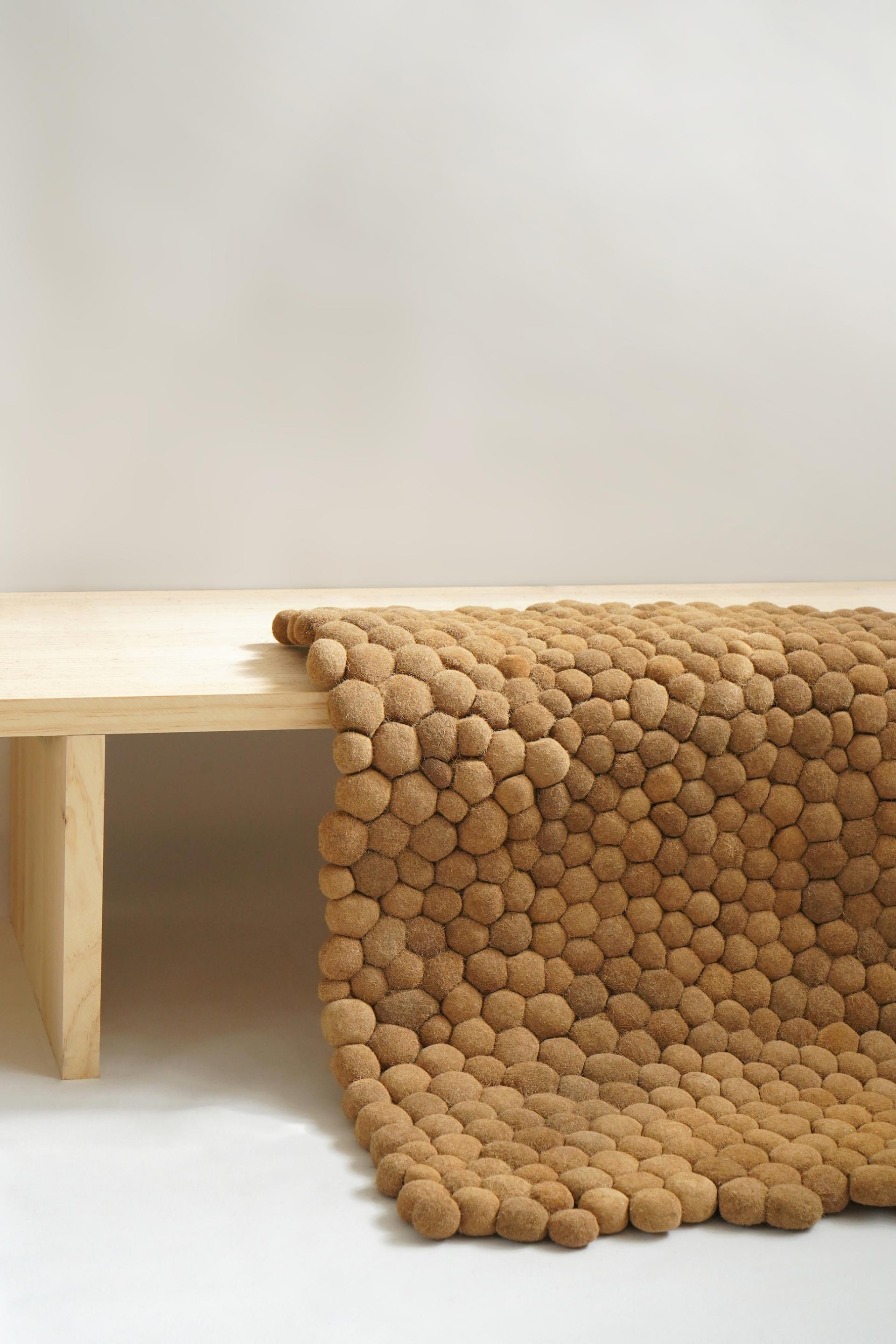 Natural seagrass rug cascading over a wooden table, highlighting eco-friendly design inspired by Posidonia from the sea.