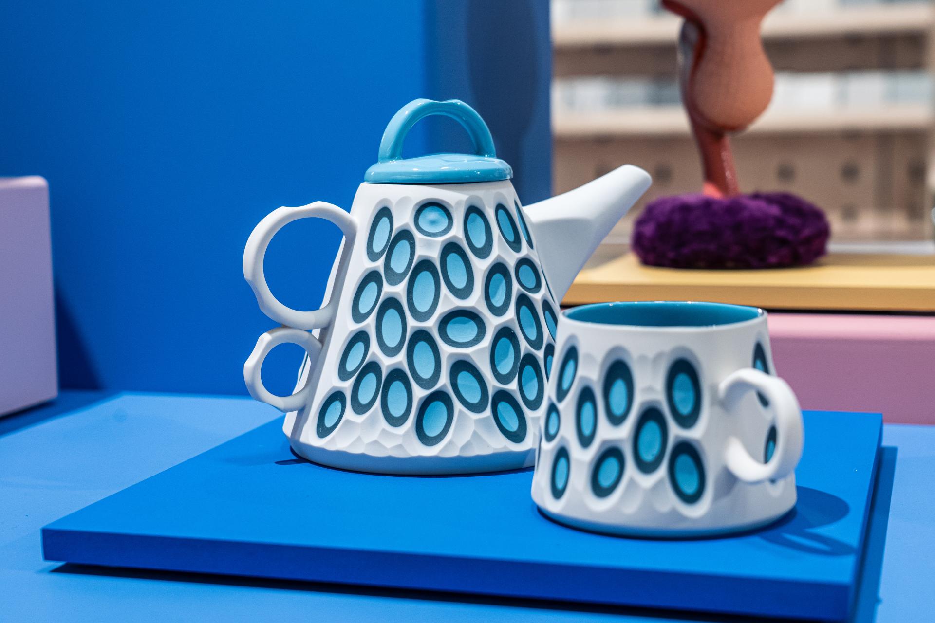 Colorful handcrafted teapot and cup displayed on a blue surface, showcasing unique Scottish design at Material Source Studio.