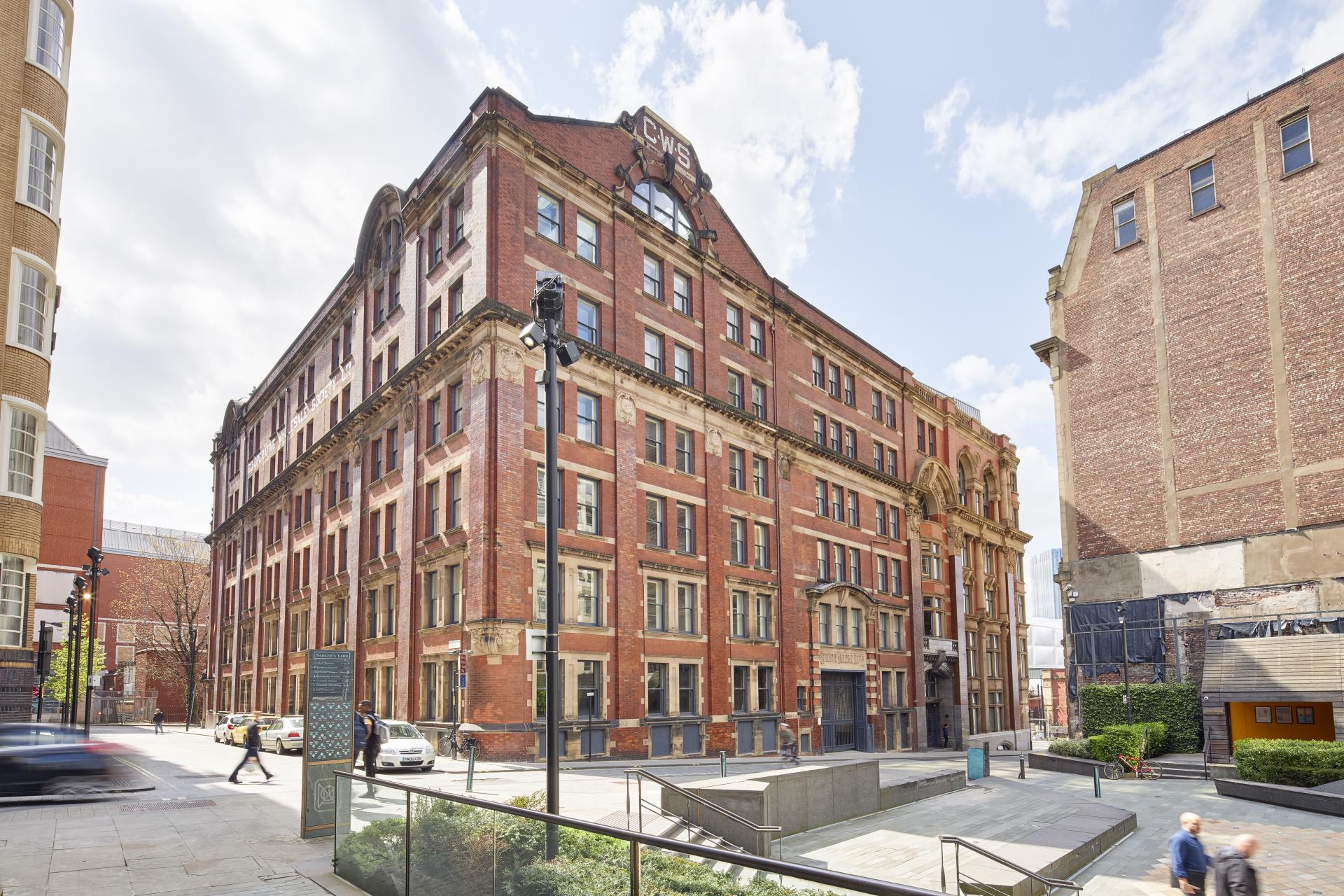 Historic red-brick building with decorative features, located in an urban setting, representing the Material Source Studio's new location.