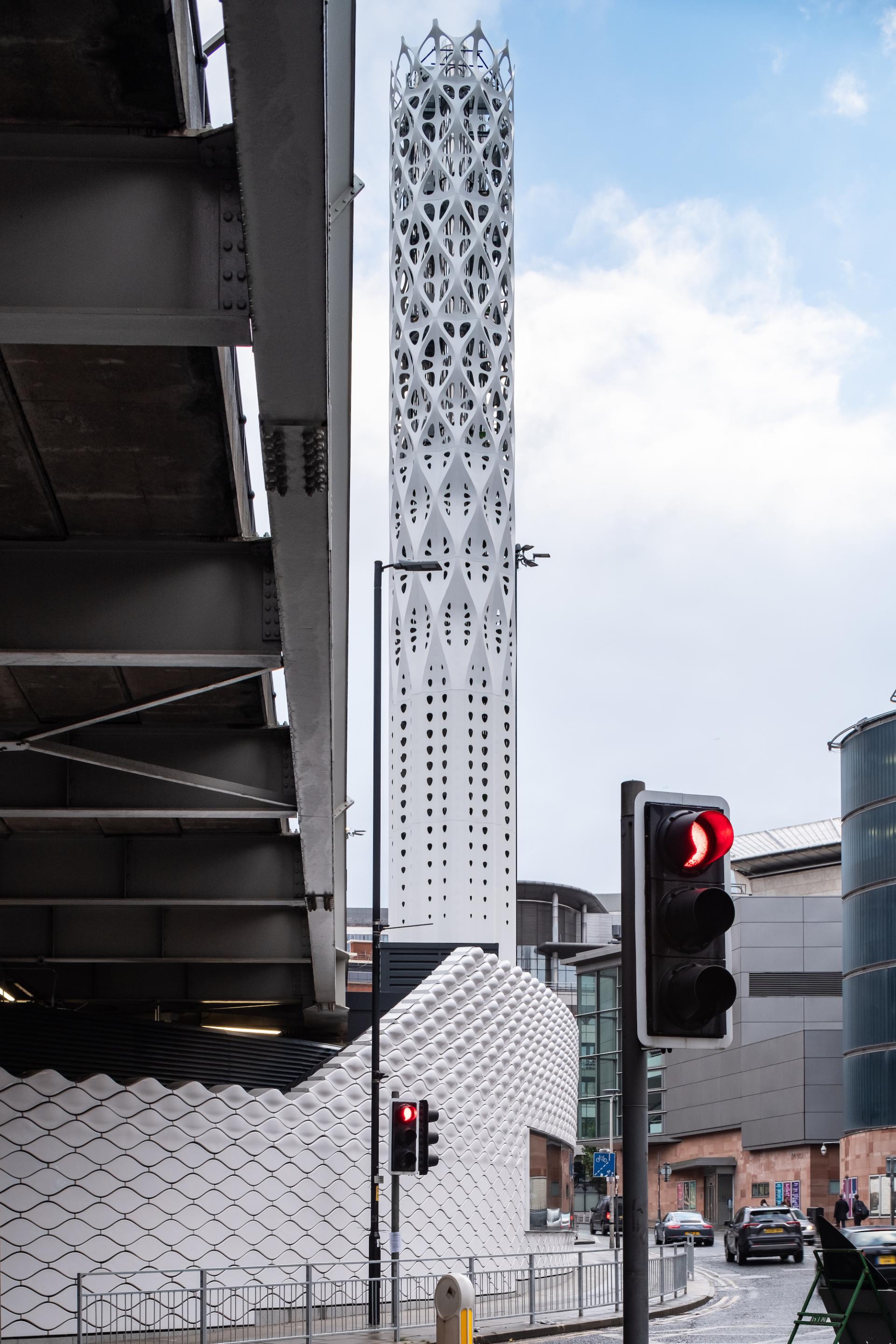 Tower of Light in Manchester, featuring intricate white design, symbolizes the city's zero-carbon ambition against an urban backdrop.