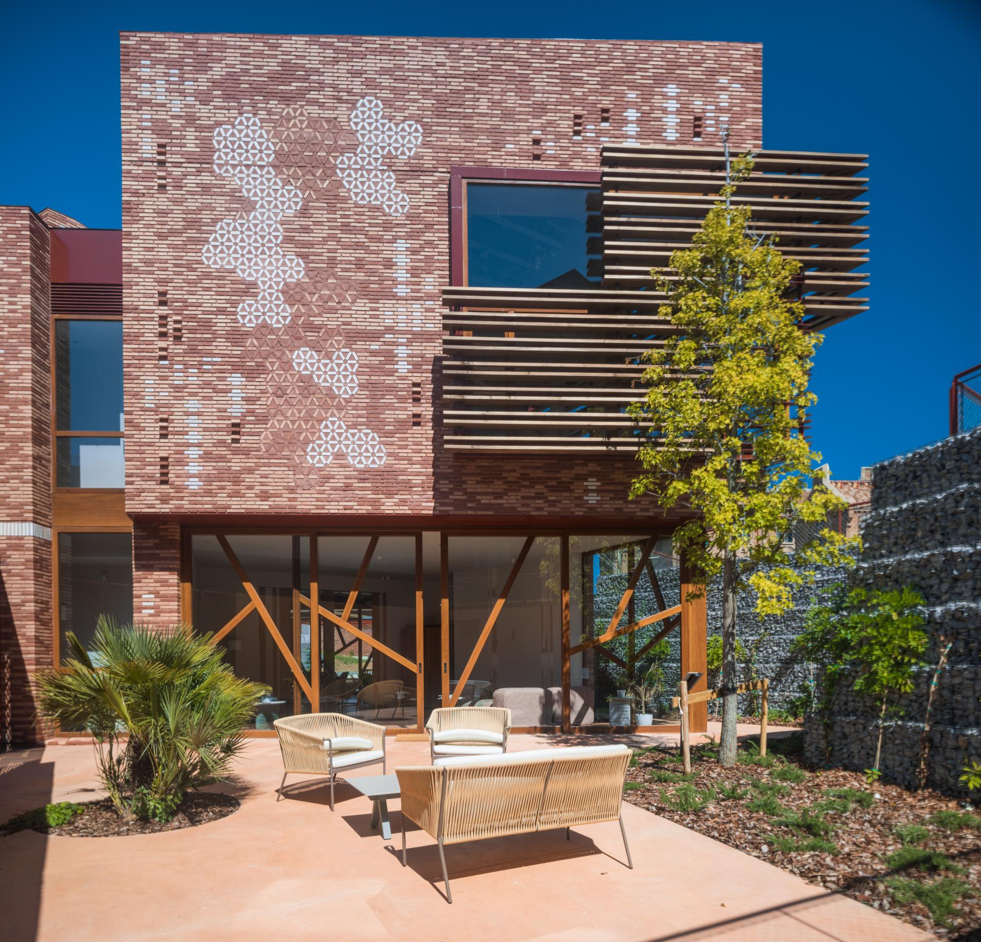 Modern Kālida Sant Pau building in Barcelona features unique brick facade and thermally modified tulipwood elements in outdoor space.