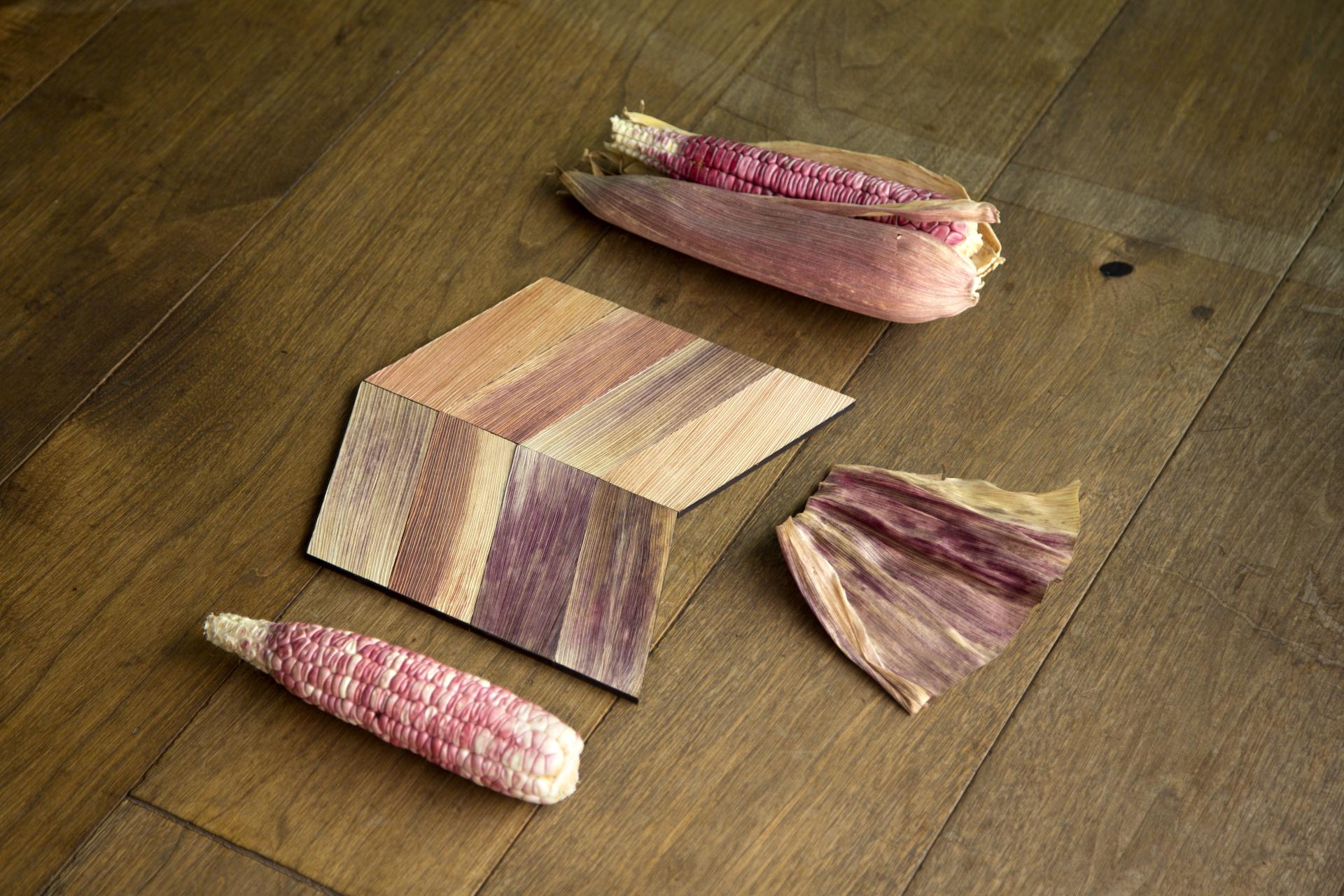 Colorful corn husks and patterned Totomoxtle material arranged on a wooden surface, showcasing sustainable design innovation.