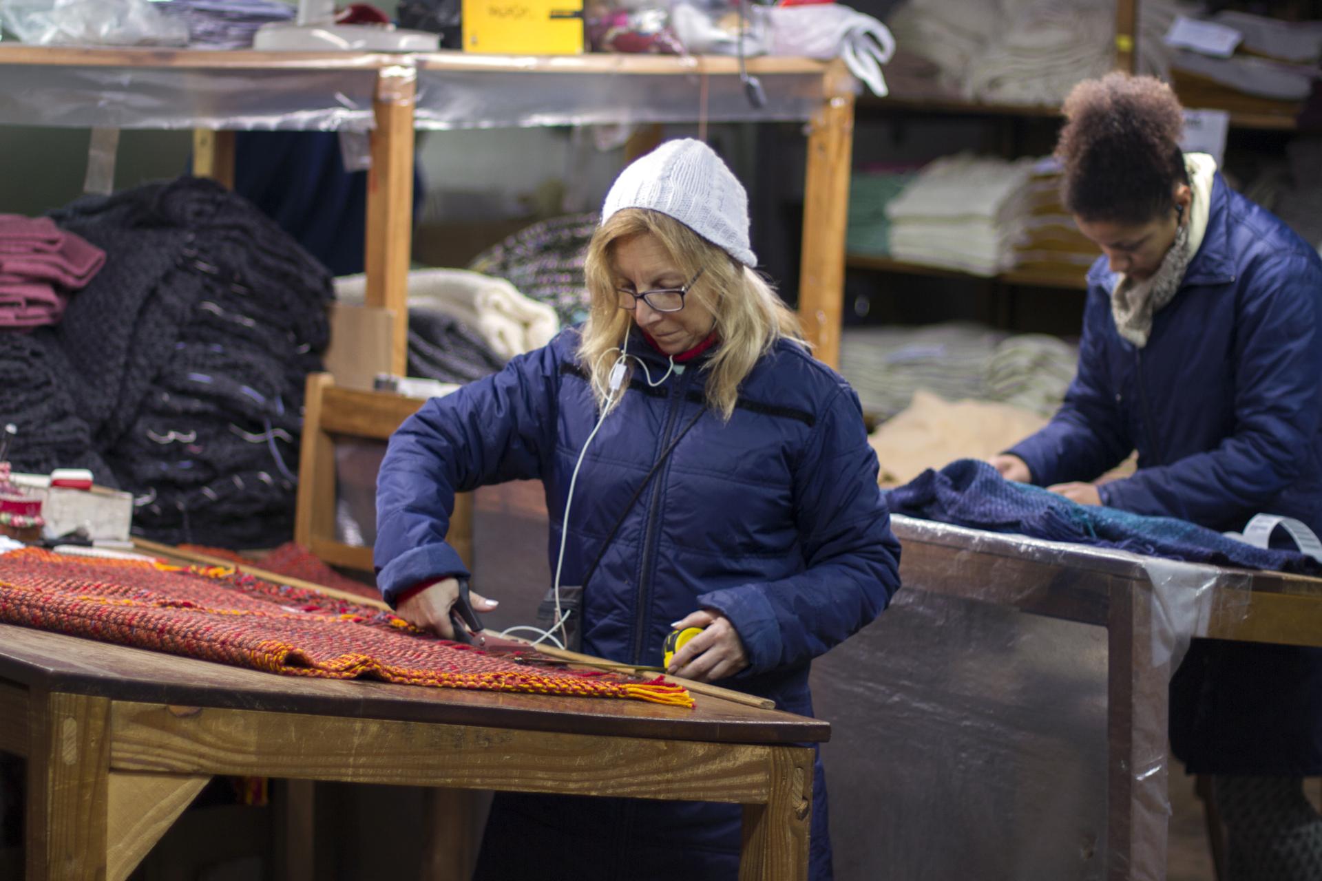 Craftspeople work on textiles, focusing on the colorful materials used for Carolina Palombo's Tutura chair design.