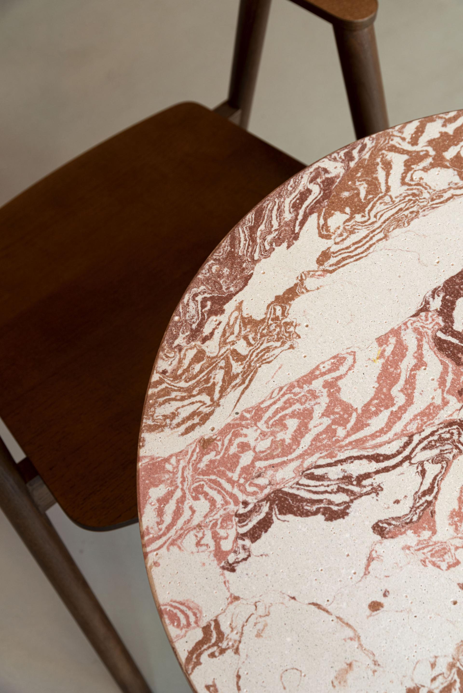 A unique concrete table featuring swirling patterns in earthy tones, showcasing the beauty of artistic design at Tosco Studio.