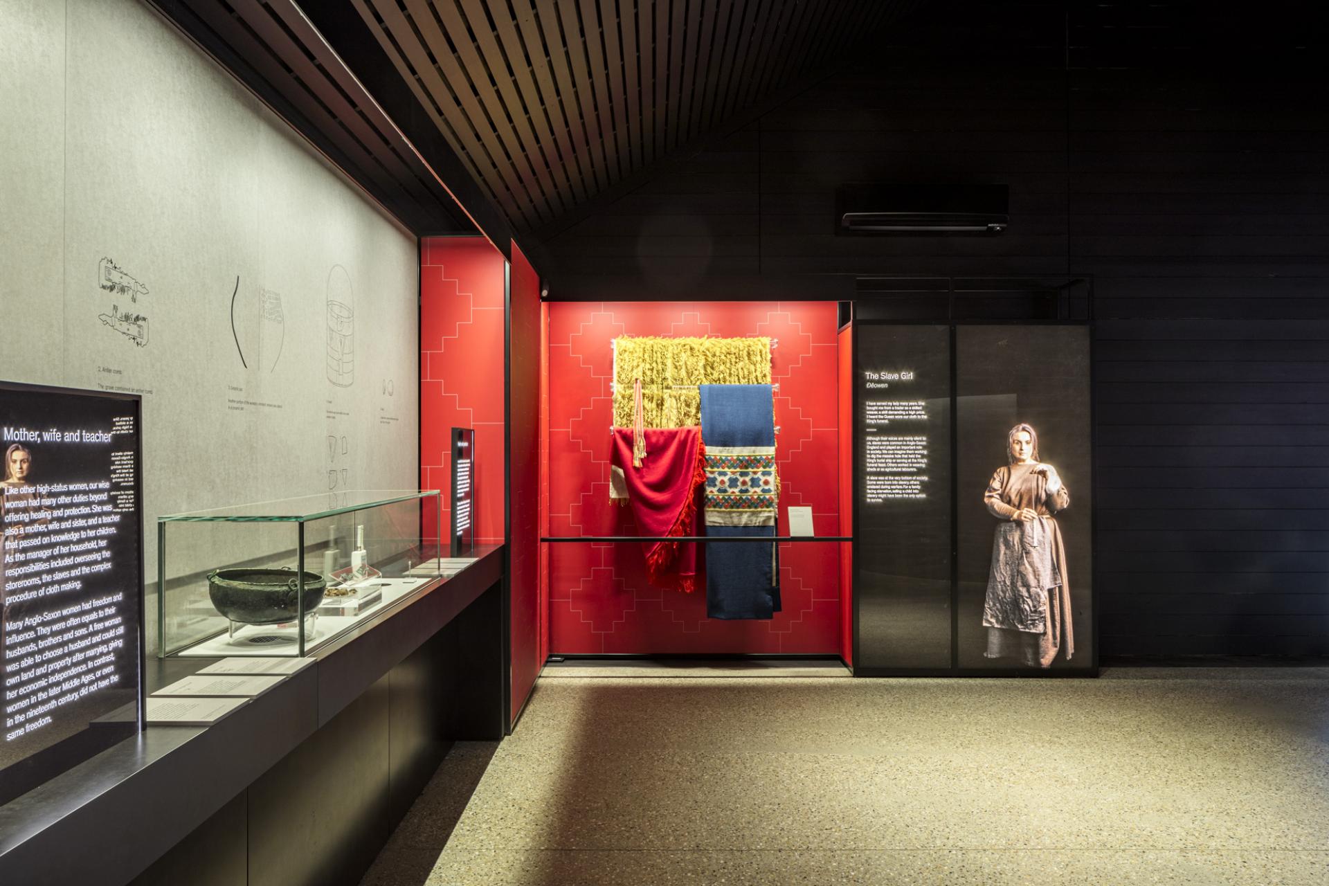 Exhibition display featuring textiles and informational panels, showcasing cultural narratives in contemporary architecture and theatre design.