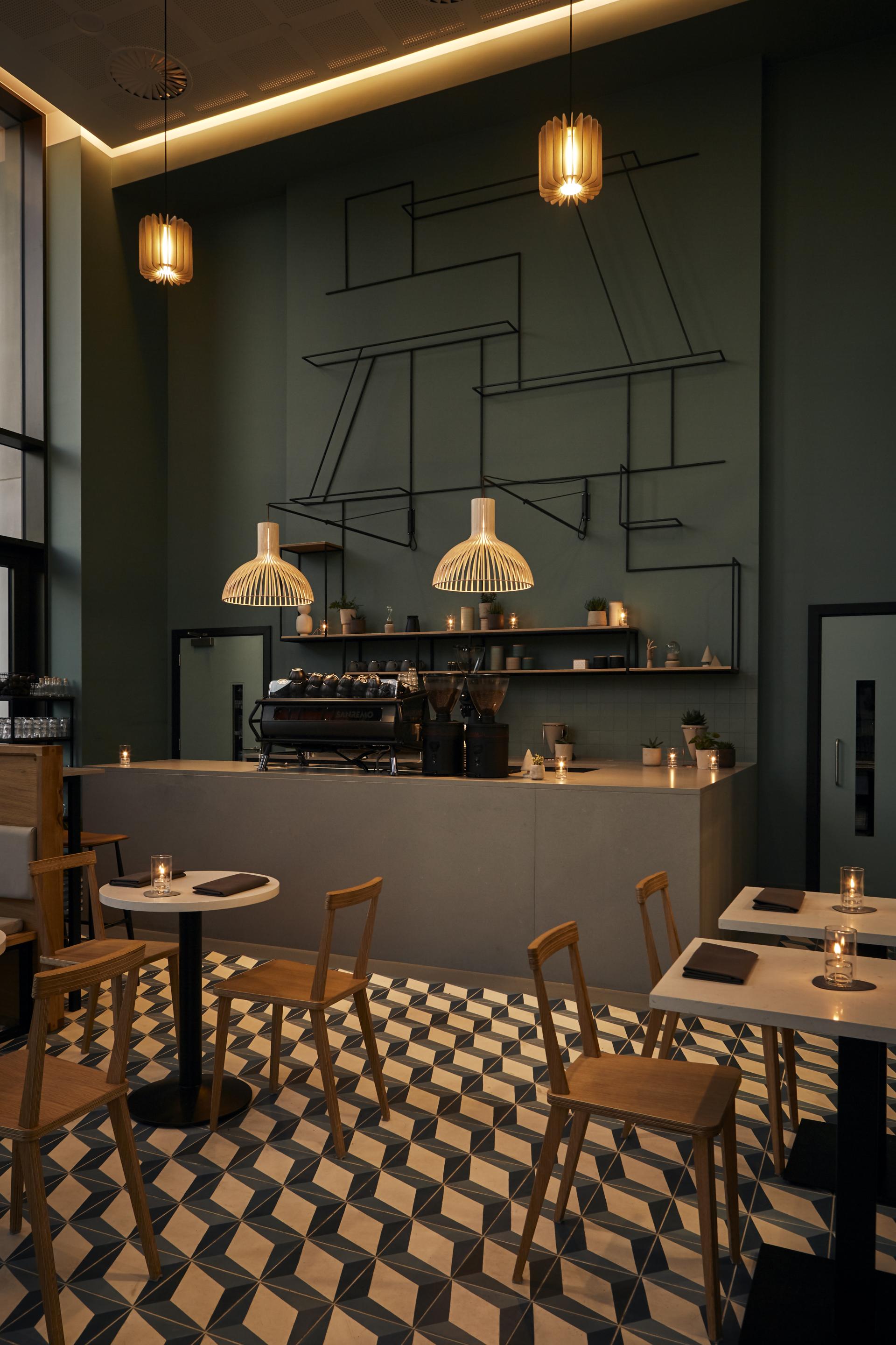 Stylish coffee shop interior featuring Caesarstone's Raw Concrete and Misty Carrera surfaces with modern furnishings and unique lighting.