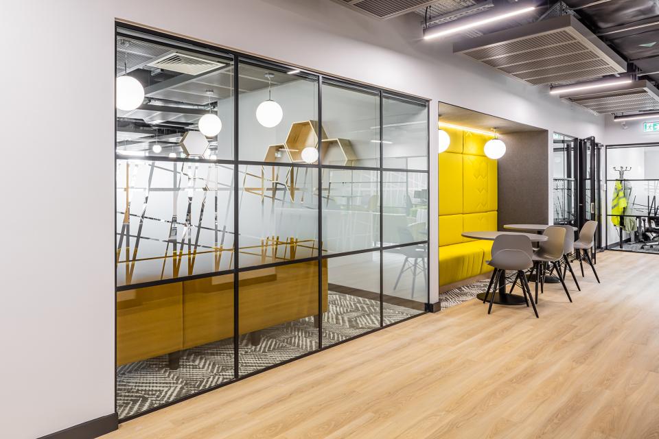 Modern collaborative workspace interior at The Bee House, featuring glass partitions and vibrant seating areas.
