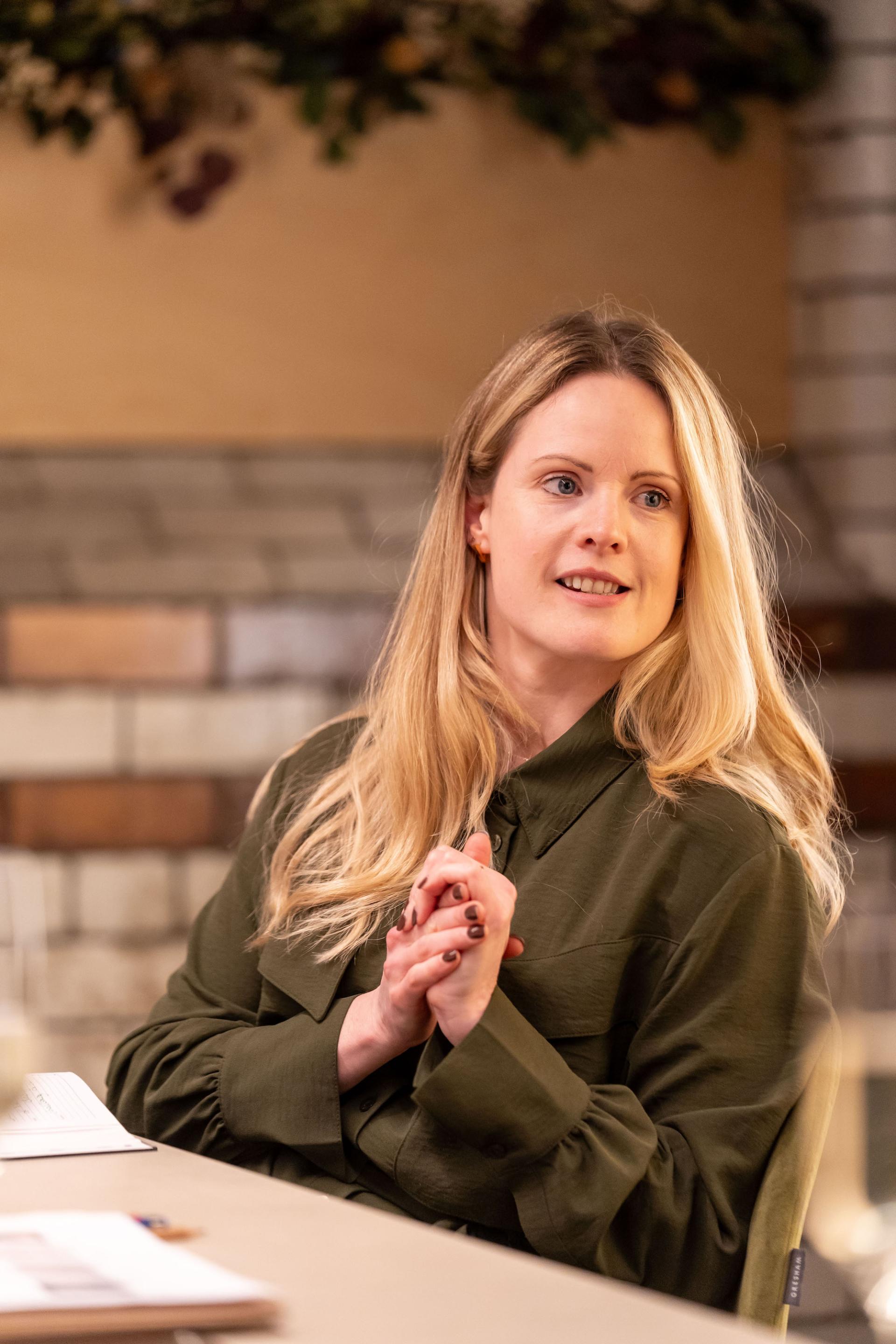 Woman with long blonde hair engaged in discussion during a sustainability and value engineering roundtable seminar.