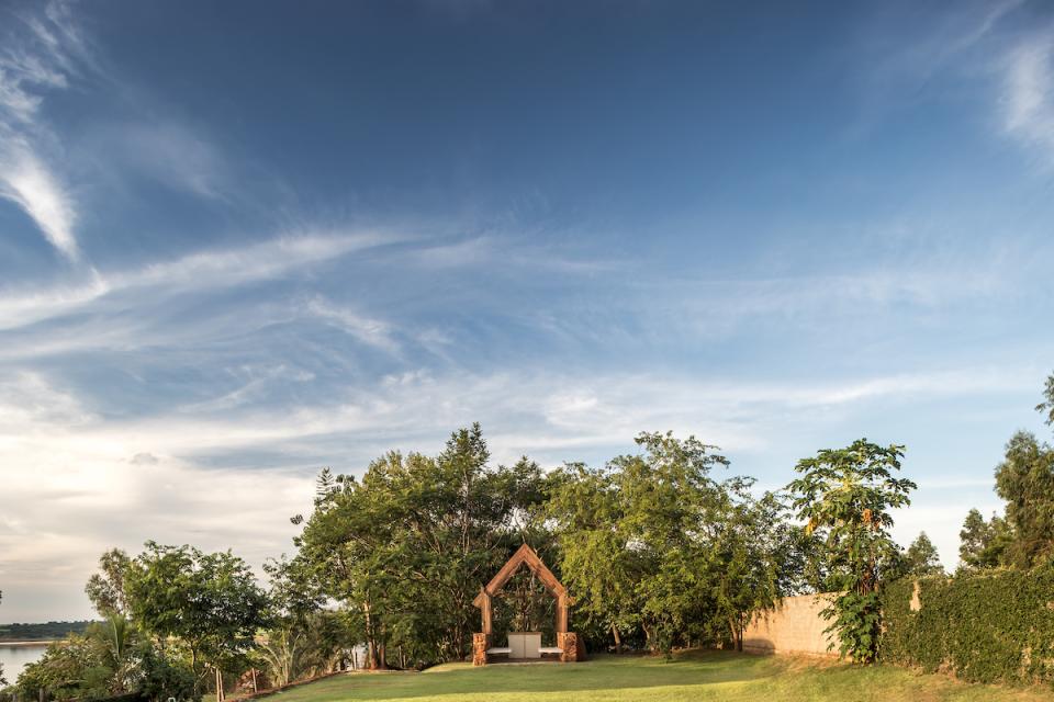 Lush greenery surrounds a serene outdoor seating area at The Lake House in Brazil, showcasing natural beauty and architectural harmony.