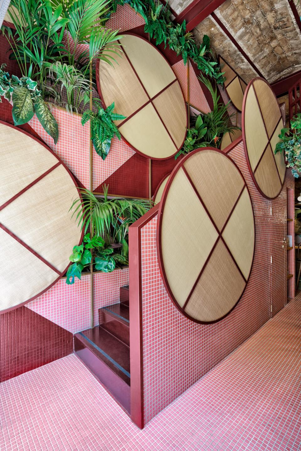 Lush tropical interior featuring circular wall decor and greenery, designed by Masquespacio for Valencia's Kaikaya restaurant.