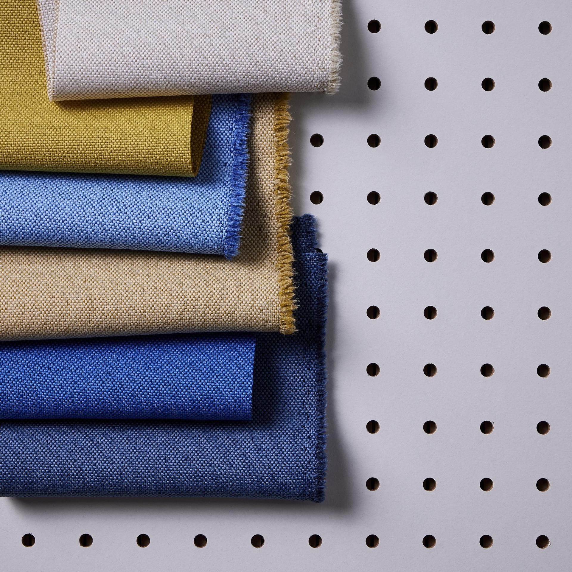 Colorful fabric samples displayed against a perforated background, representing Camira's commitment to eco-friendly materials and marine sustainability.