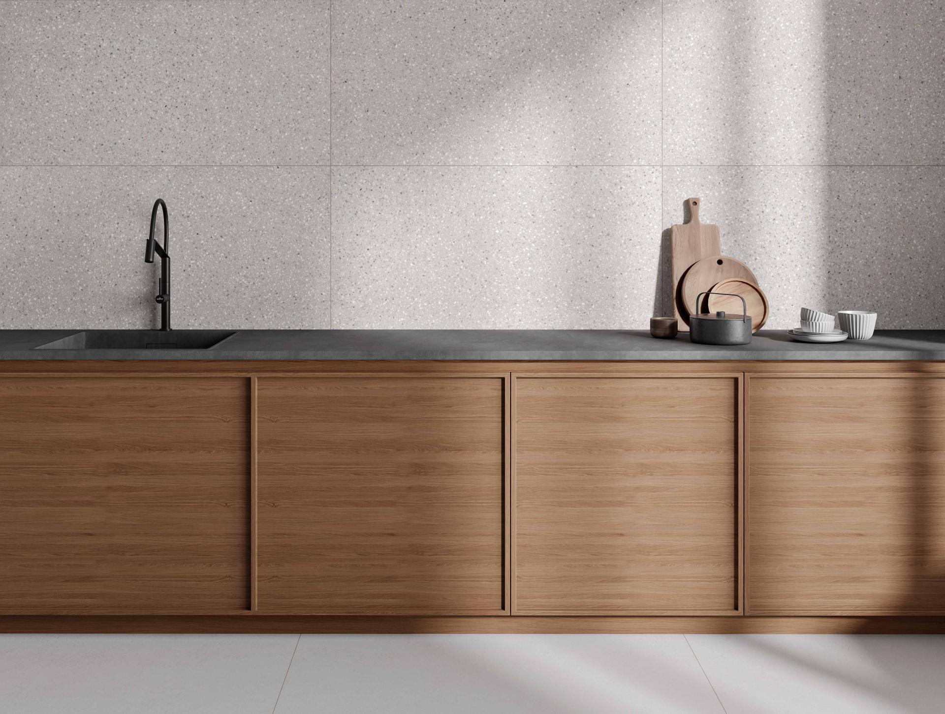 Stylish kitchen featuring terrazzo wall tiles, a minimalist wooden cabinetry design, and elegant tableware on a concrete countertop.