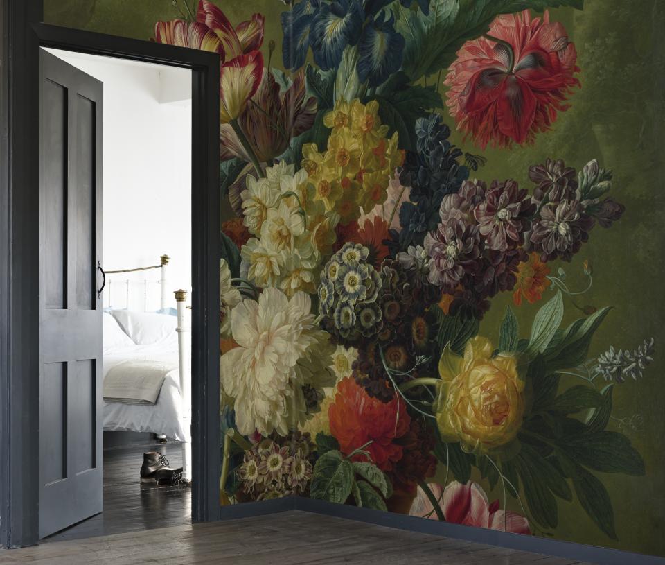 Luxurious floral wallpaper in rich colors adorns the wall, creating a dramatic backdrop for a cozy bedroom setting.