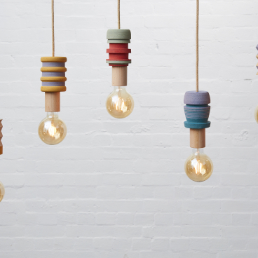Colorful pendant lights with innovative designs hanging against a white brick wall, showcasing modern luxury and style.