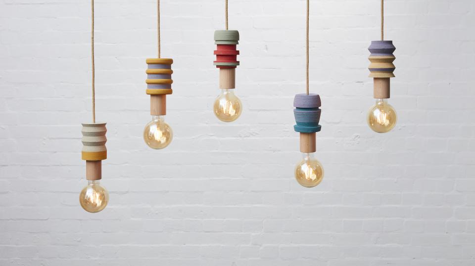 Colorful pendant lights with innovative designs hanging against a white brick wall, showcasing modern luxury and style.