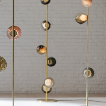 Elegant floor lamps with colorful glass globes and brass stands, showcasing Bocci's innovative design and craftsmanship.