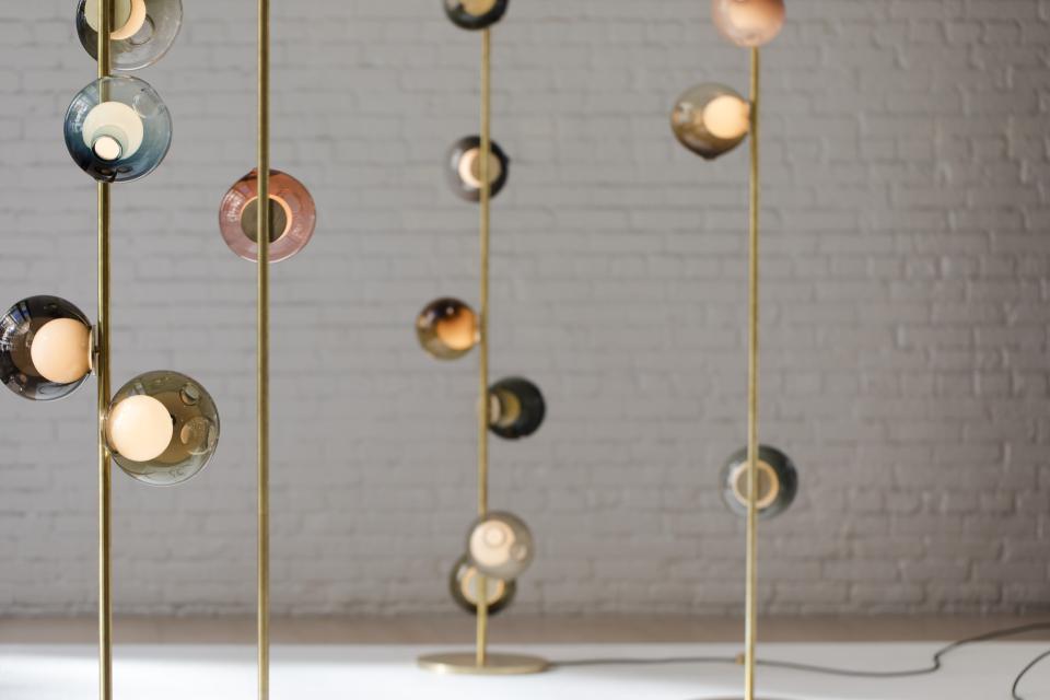Elegant floor lamps with colorful glass globes and brass stands, showcasing Bocci's innovative design and craftsmanship.