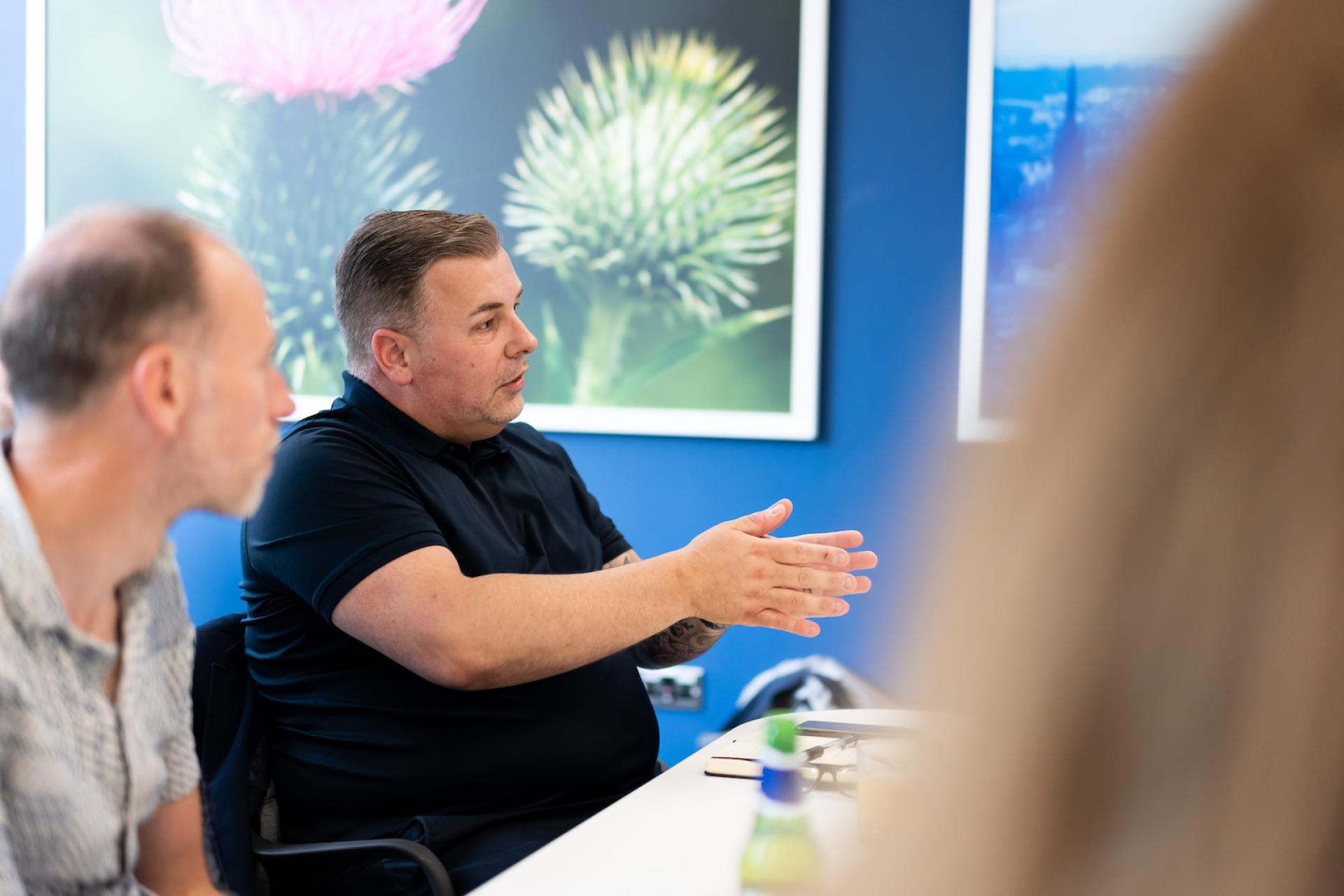 Participants engage in a collaborative discussion about technology in a modern office setting with vibrant artwork on the walls.