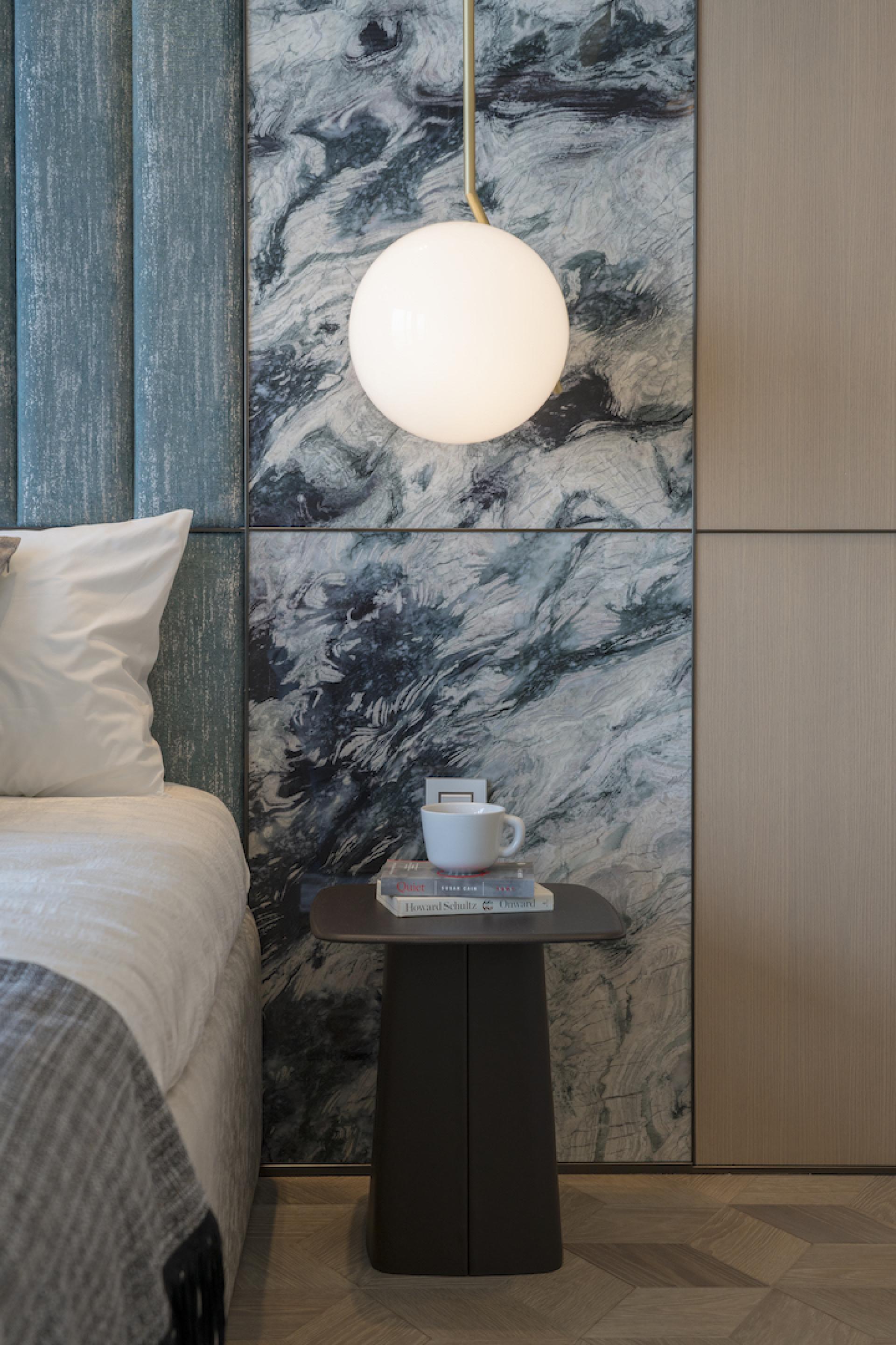 Stylish bedroom corner in a Hong Kong apartment featuring a modern lamp, decorative wall, and elegant side table with coffee.