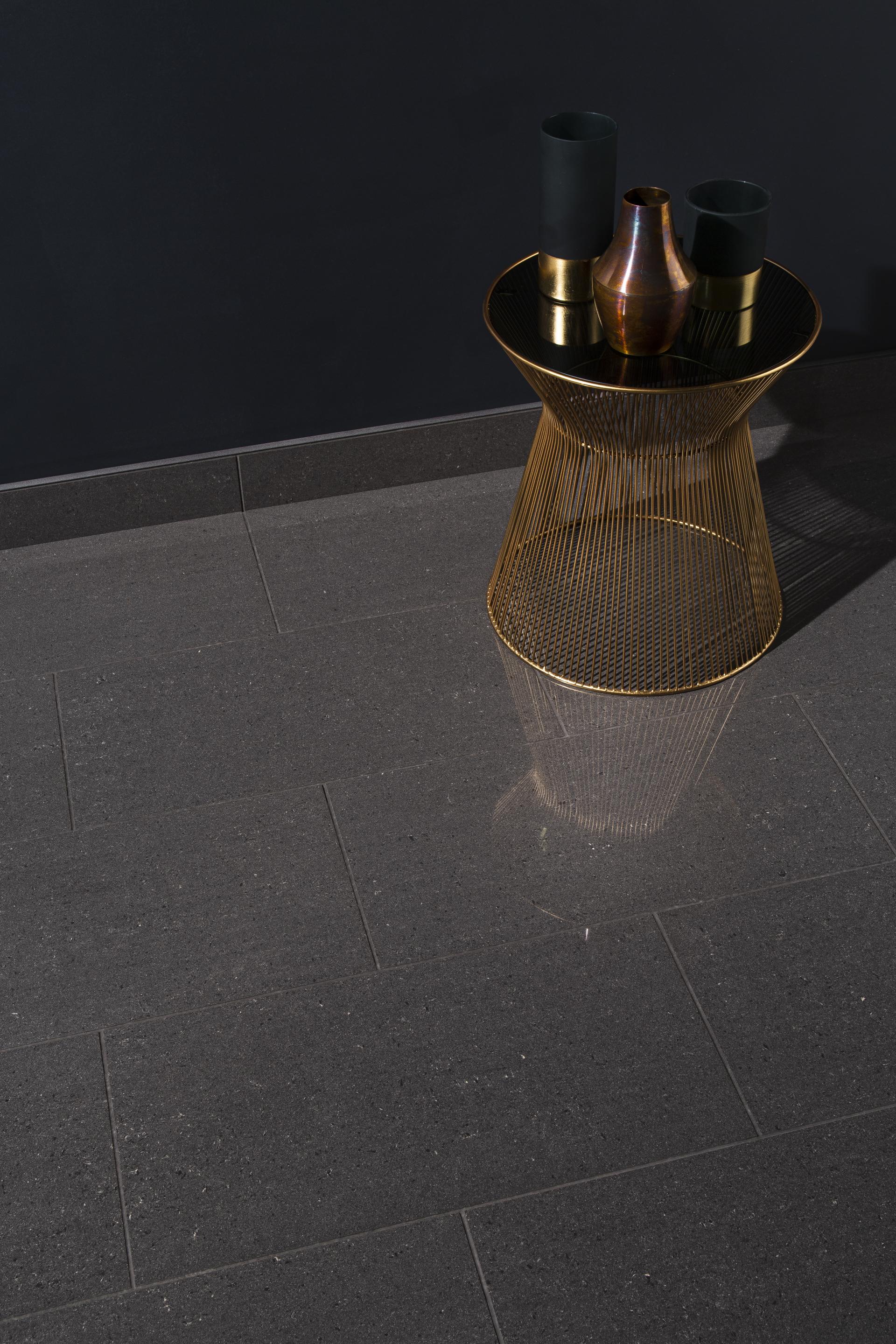 Stylish interior featuring sleek dark tile flooring and a modern gold accent table with decorative vases.