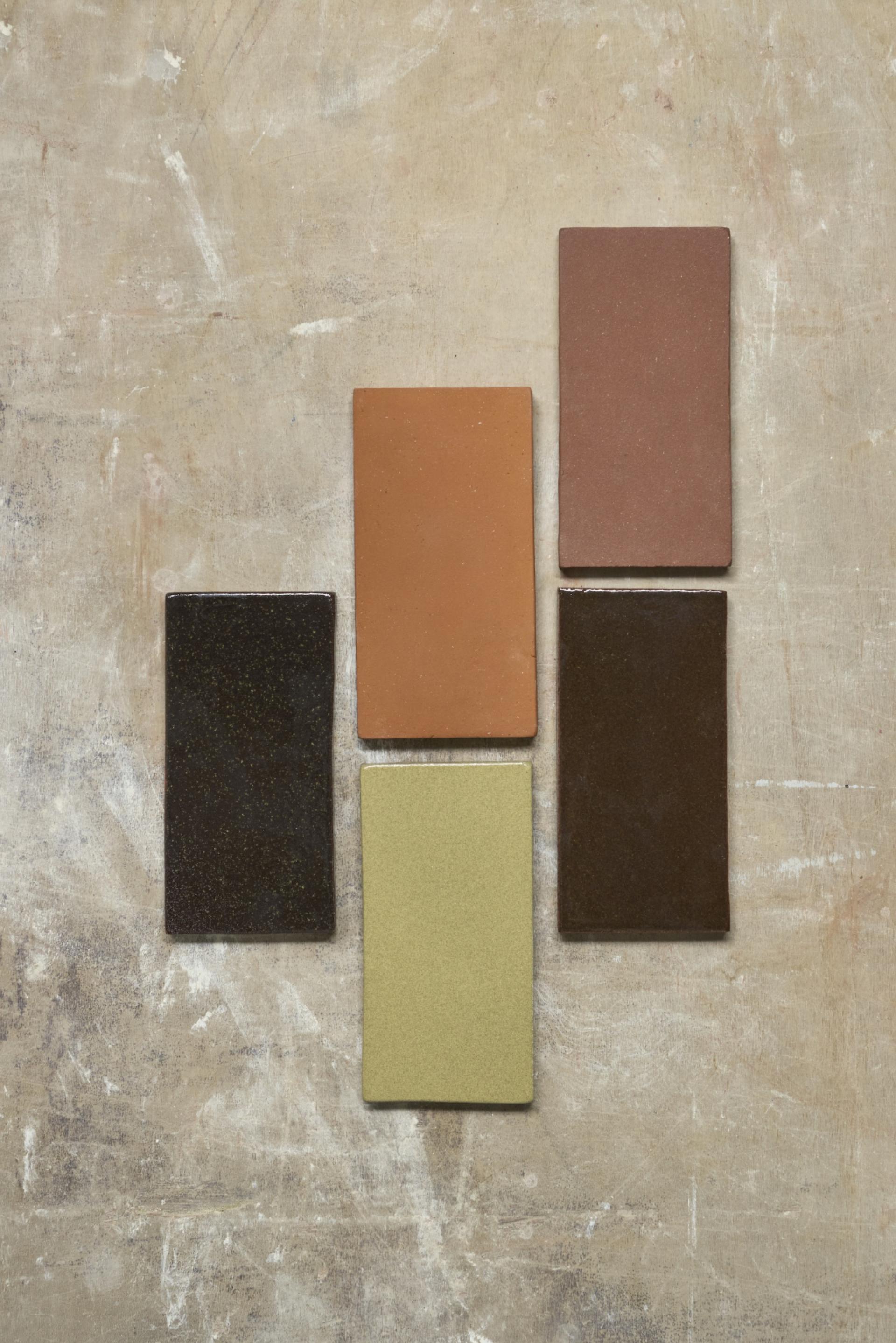 Colorful ceramic tiles arranged artistically on a textured surface, representing design elements in London Underground's metro system.